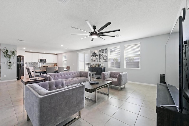 living room with a textured ceiling, light tile patterned flooring, and ceiling fan