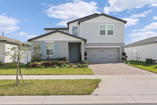 112 Towns, Haines City, FL 33844 - view of front of property with decorative driveway, a front lawn, board and batten siding, a garage, and stucco siding