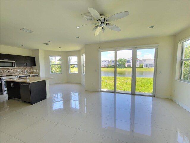 tiled spare room featuring ceiling fan and a water view