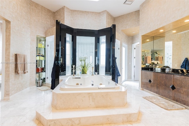 bathroom featuring tiled tub, vanity, and a towering ceiling