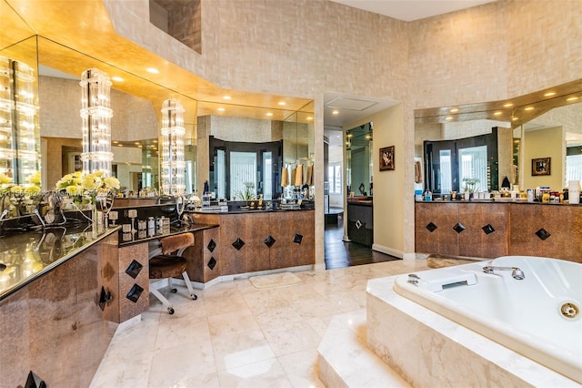 bathroom featuring a high ceiling, vanity, and tiled bath