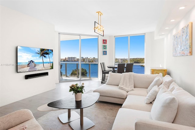 living room with an inviting chandelier, a water view, light tile floors, and expansive windows