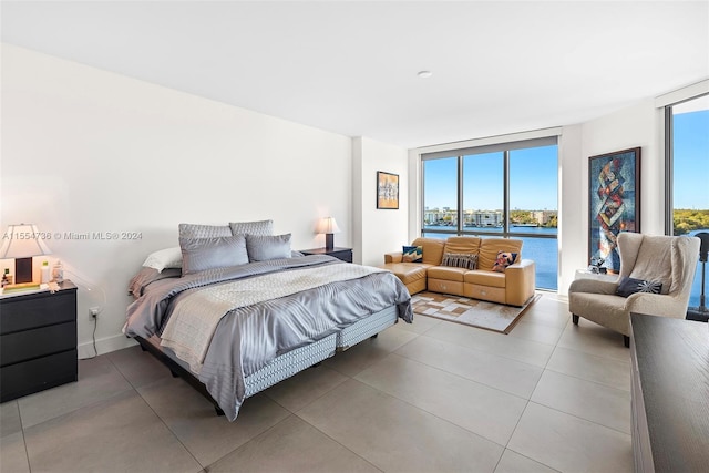 tiled bedroom featuring expansive windows, a water view, and multiple windows