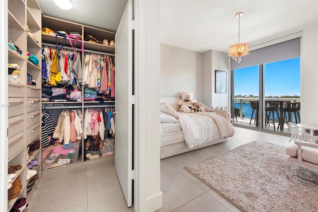 tiled bedroom with access to exterior, a notable chandelier, a water view, and a closet