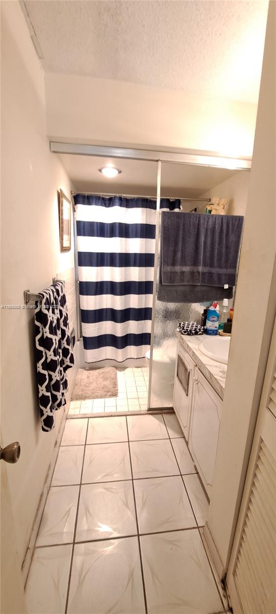 bathroom with a textured ceiling, vanity, and a shower with curtain