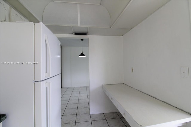 interior space with white cabinetry, white refrigerator, light tile floors, and pendant lighting