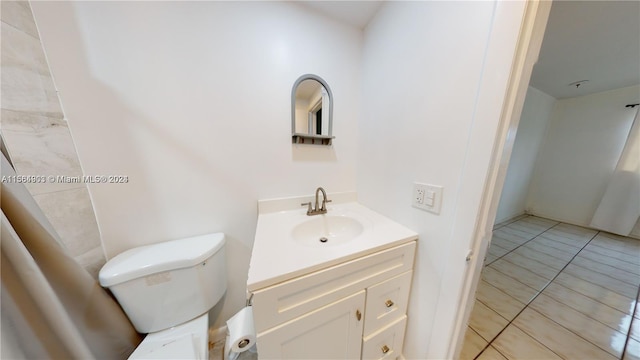 bathroom with tile flooring, toilet, and vanity