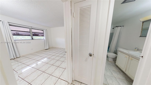 bathroom featuring tile flooring, a textured ceiling, toilet, and vanity