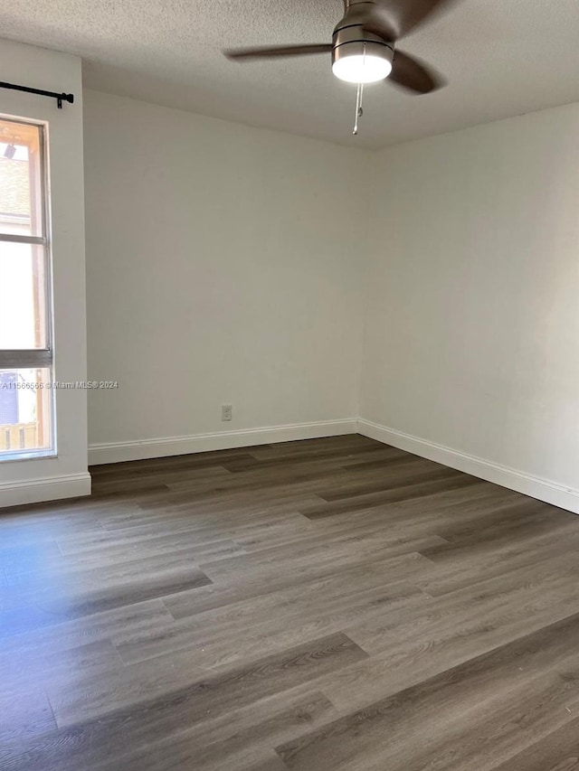 spare room with a textured ceiling, ceiling fan, and dark wood-type flooring