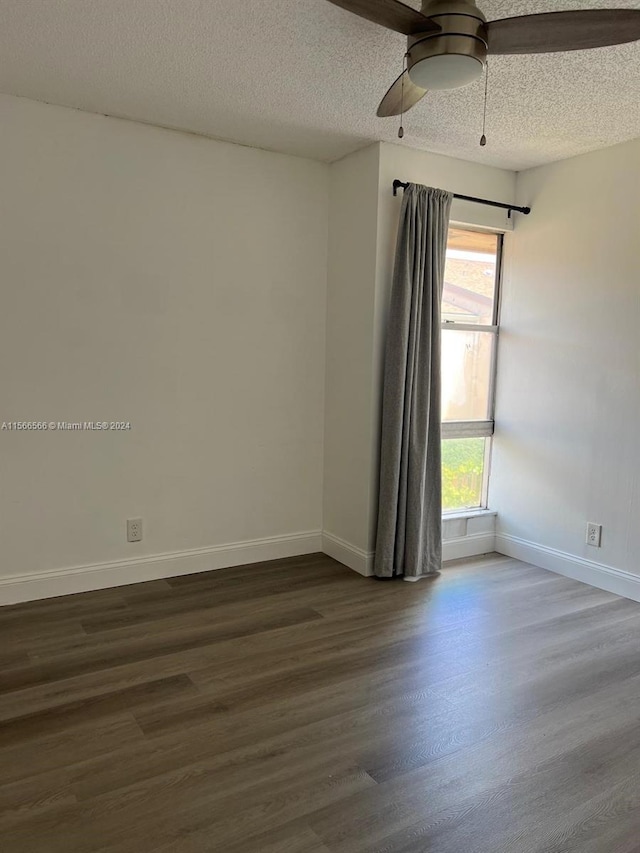 spare room with a textured ceiling, ceiling fan, and dark wood-type flooring