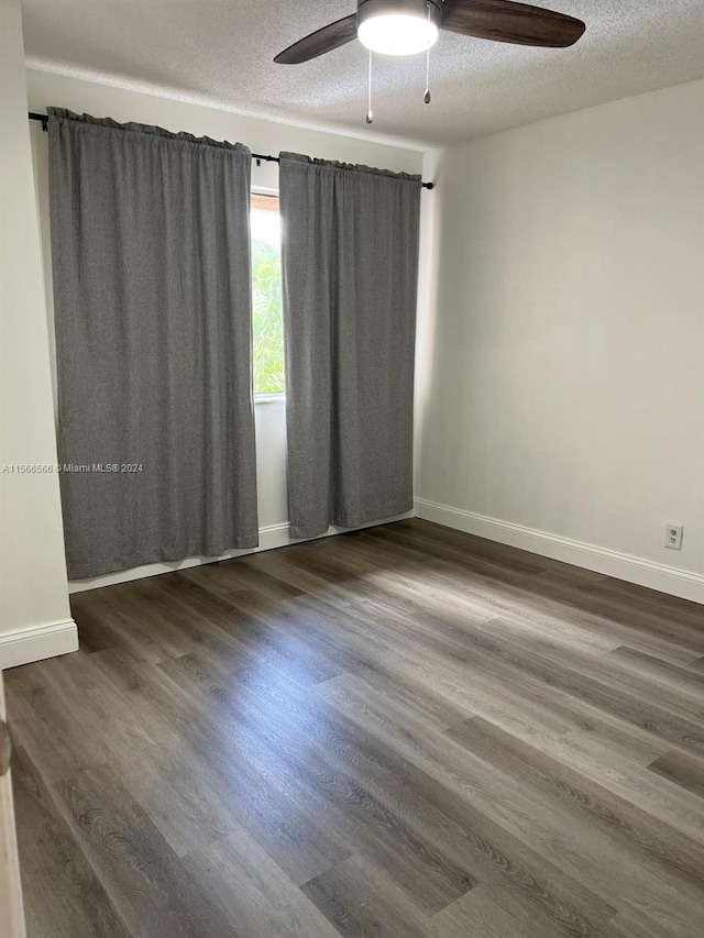 unfurnished room featuring a textured ceiling, ceiling fan, and dark wood-type flooring