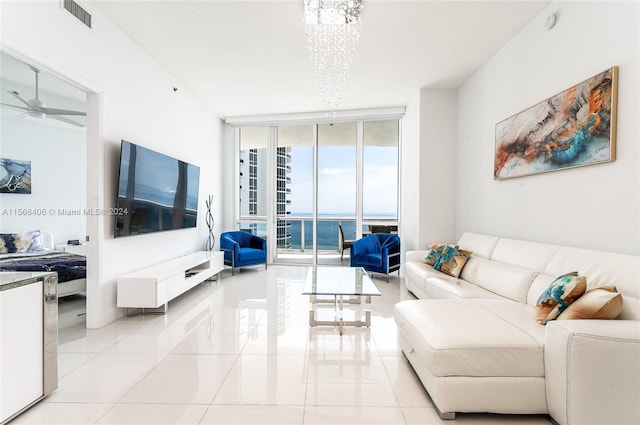 living room with floor to ceiling windows, a water view, light tile floors, and ceiling fan with notable chandelier