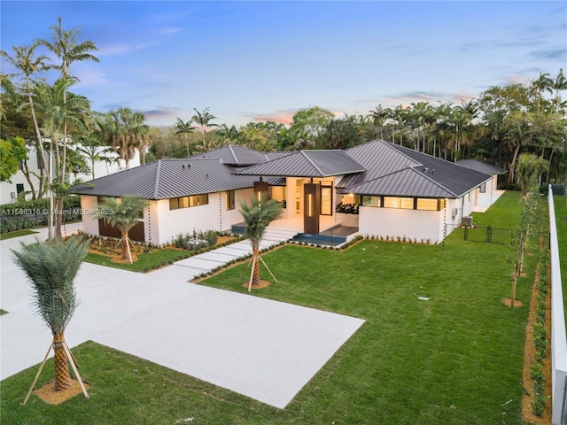 view of front of home with stucco siding, a lawn, a standing seam roof, fence, and metal roof