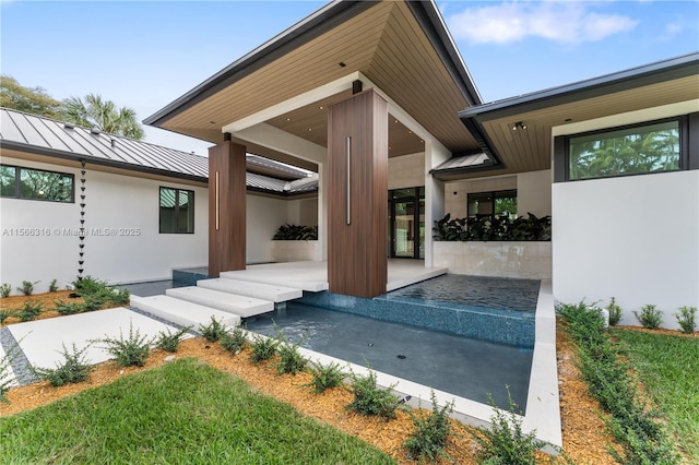 entrance to property featuring a standing seam roof, metal roof, and stucco siding