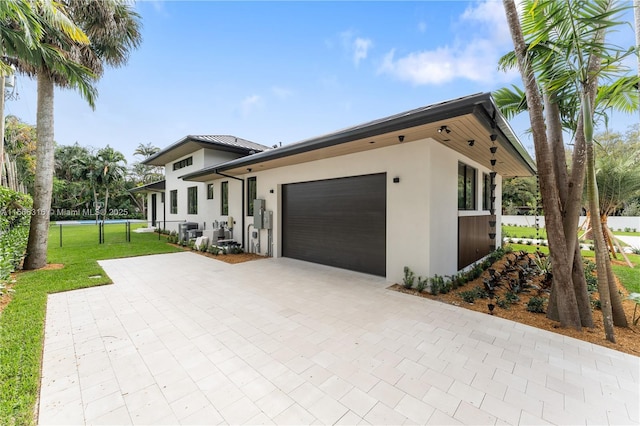 view of front of property with an attached garage, fence, decorative driveway, stucco siding, and a front yard