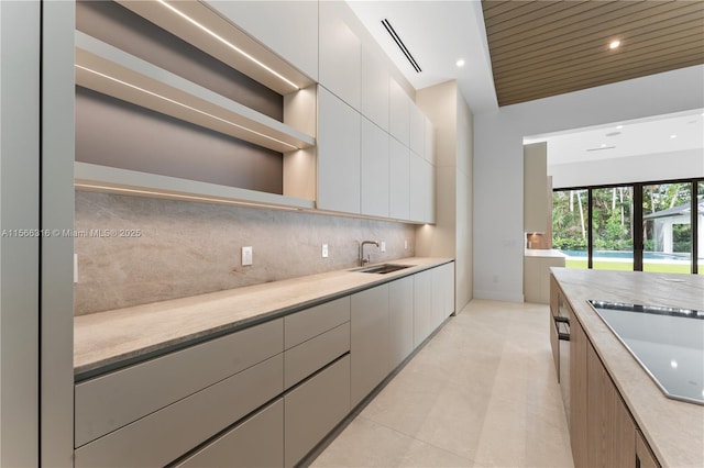 kitchen featuring black electric cooktop, modern cabinets, light countertops, and a sink