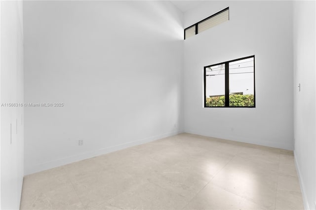 empty room with a towering ceiling and baseboards