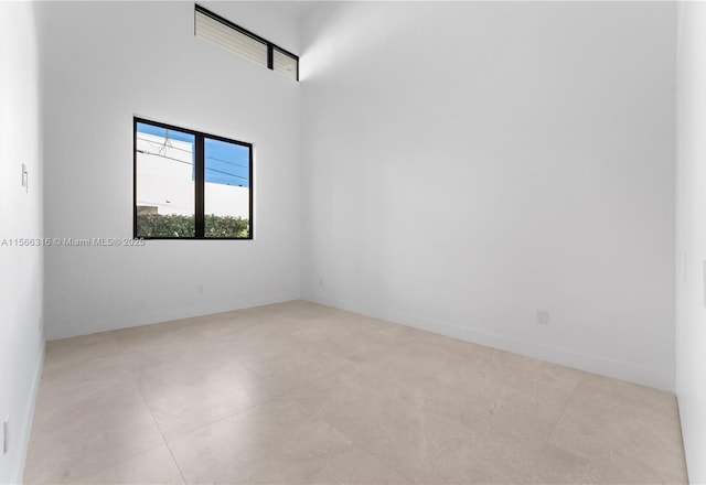 unfurnished room with a towering ceiling and baseboards