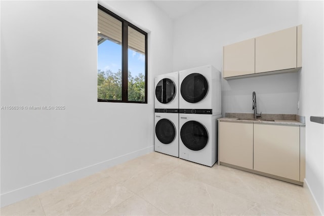 laundry room featuring stacked washer / drying machine, cabinet space, a sink, and baseboards