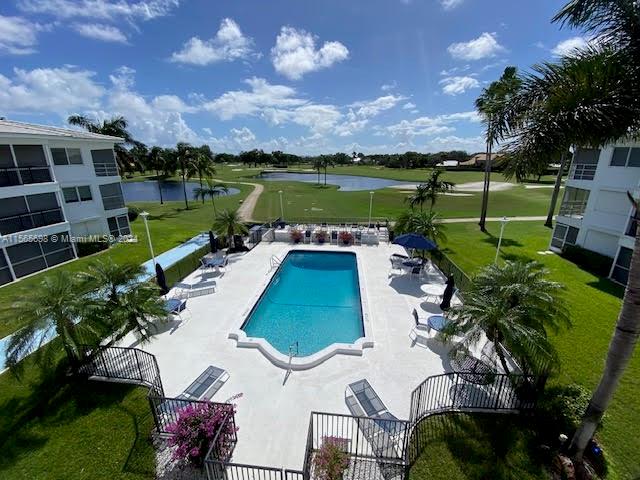 view of pool featuring a patio area, a water view, and a lawn