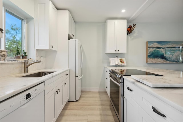 kitchen with light stone counters, sink, white cabinets, white appliances, and light hardwood / wood-style flooring