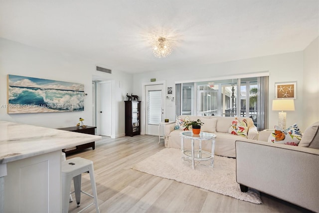 living room featuring light wood-type flooring and a chandelier