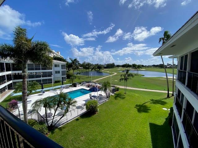 view of pool with a lawn and a water view