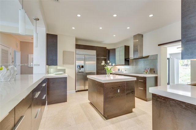 kitchen with tasteful backsplash, a center island, built in refrigerator, light tile floors, and wall chimney exhaust hood