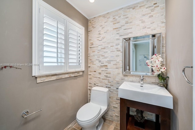 bathroom with tile flooring, tile walls, toilet, vanity, and crown molding