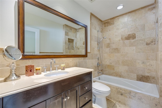 full bathroom featuring toilet, tiled shower / bath, large vanity, backsplash, and tile walls