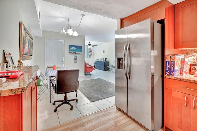 interior space featuring light hardwood / wood-style flooring, ceiling fan with notable chandelier, and a textured ceiling