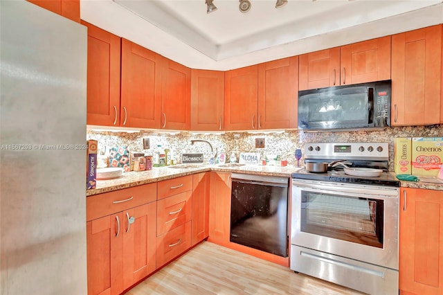 kitchen featuring light stone countertops, black appliances, tasteful backsplash, sink, and light wood-type flooring