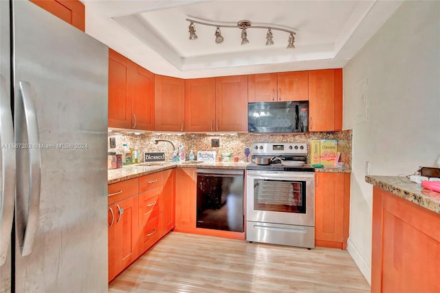 kitchen with light wood-type flooring, track lighting, a tray ceiling, and black appliances