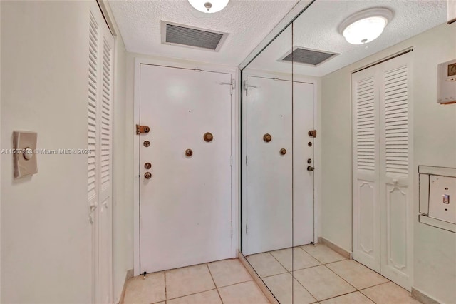 hallway with light tile floors and a textured ceiling