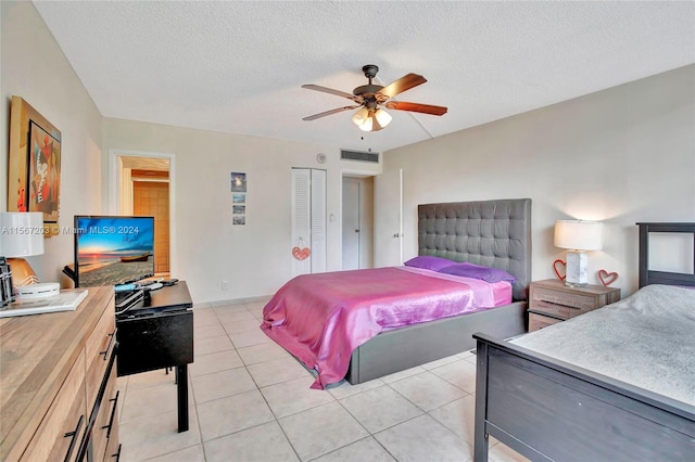 tiled bedroom featuring a closet, ceiling fan, and a textured ceiling