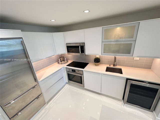 kitchen with white cabinets, stainless steel appliances, sink, and beverage cooler