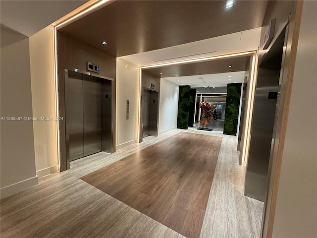 corridor featuring light wood-type flooring and elevator