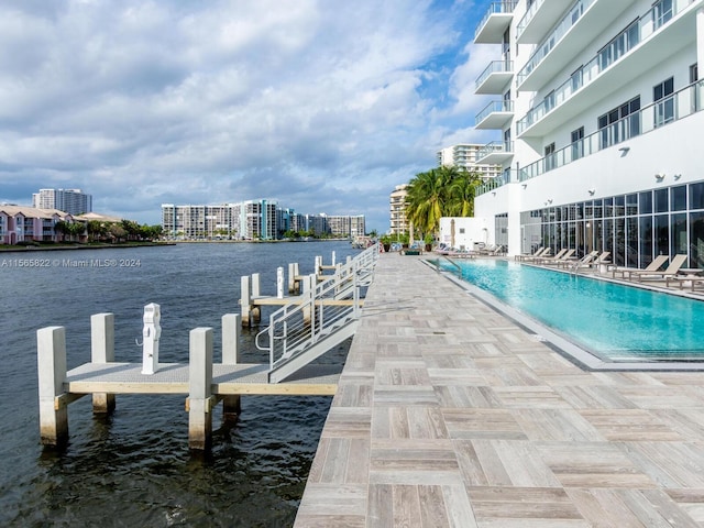 view of dock with a water view and a community pool