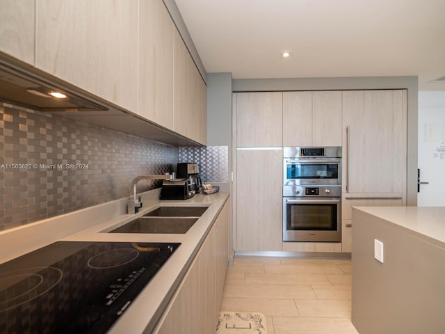 kitchen featuring tasteful backsplash, black electric stovetop, stainless steel double oven, light brown cabinetry, and sink