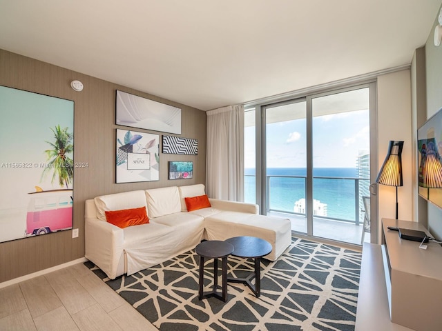 living room with floor to ceiling windows, a water view, and light hardwood / wood-style flooring