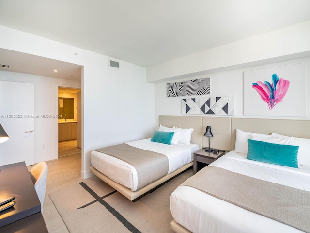 bedroom featuring light hardwood / wood-style flooring and ensuite bathroom