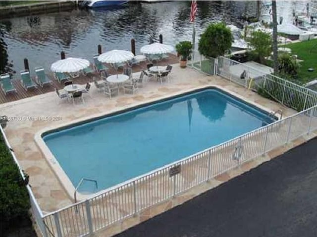 view of pool featuring a patio, a water view, fence, and a fenced in pool