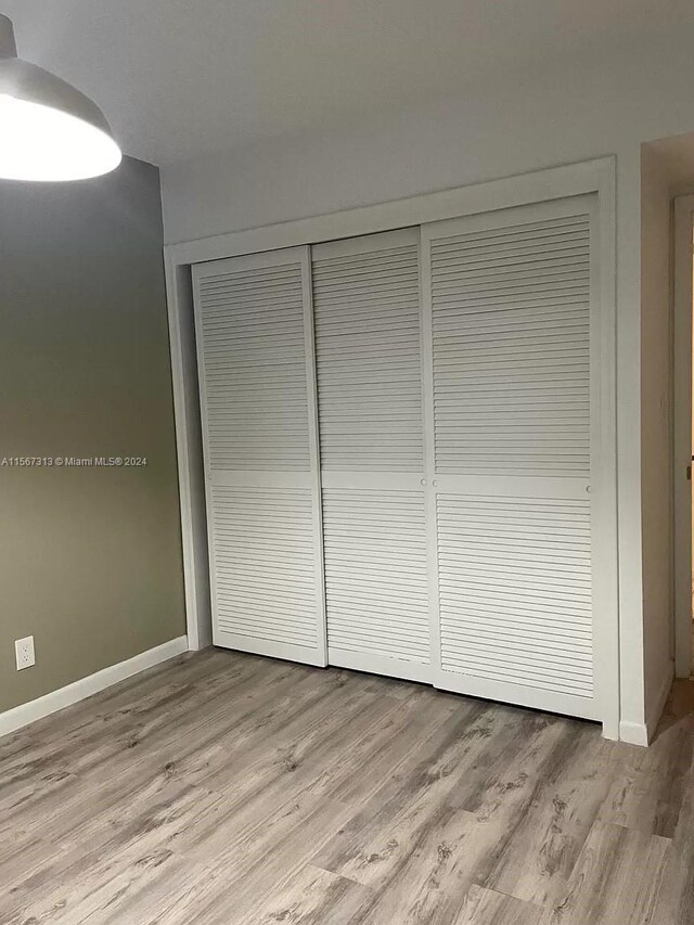 unfurnished bedroom with light hardwood / wood-style floors and a closet