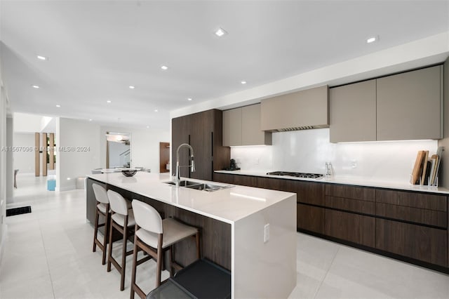 kitchen featuring a breakfast bar area, sink, light tile flooring, and a kitchen island with sink