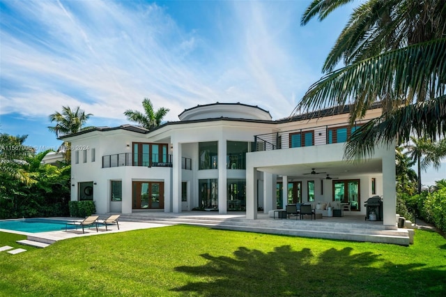 back of property featuring ceiling fan, a lawn, a balcony, and a patio