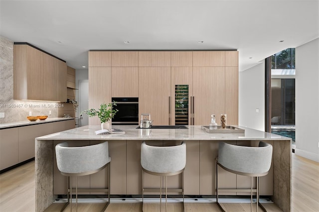 kitchen with a large island, a kitchen bar, light hardwood / wood-style floors, and oven