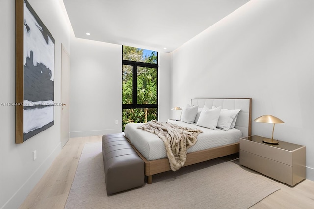 bedroom with expansive windows and light hardwood / wood-style flooring