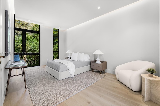 bedroom with a wall of windows and light hardwood / wood-style flooring