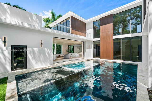 back of property with a balcony and an outdoor living space