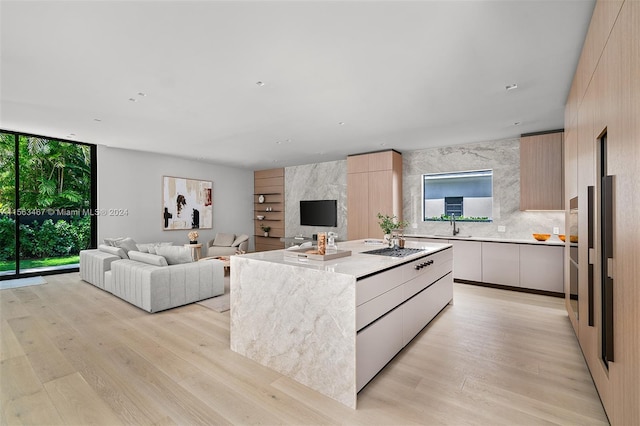 kitchen featuring light hardwood / wood-style floors, a high end fireplace, black gas cooktop, and a kitchen island